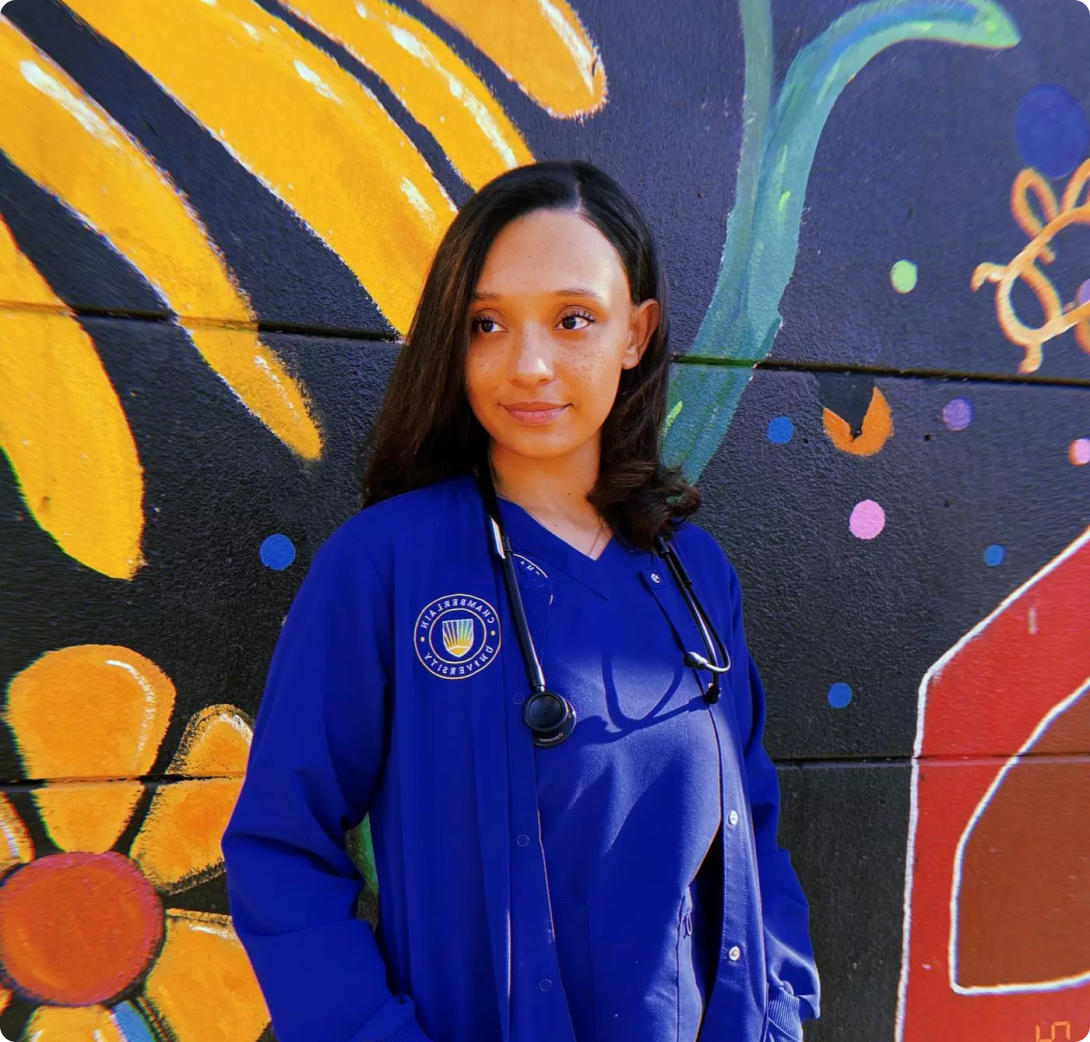 Chamberlain nurse in blue sweater standing in front of a colorful mural