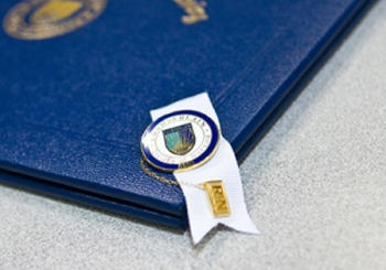 Diploma with Chamberlain grad pin on the corner