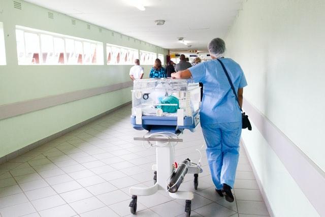 nurse walking down a hospital hallway with a bassinet