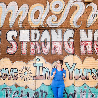 Nurse leaning up against wall with inspiring mural