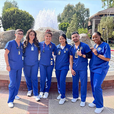 group of smiling nurses posing next to a fountain