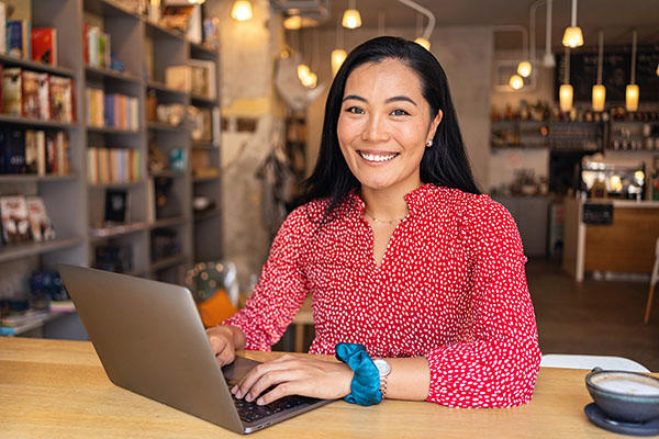 Smiling women in bright red blouse on her laptop at a local coffee shop
